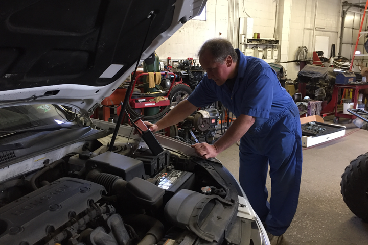 Ken Gardner using the computer diagnostic tool to diagnose a car engine problem at Kenny’s Garage Auto Repair and Maintenance Shop at 2316 McKinley Avenue Erie PA 16503.